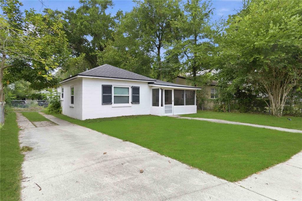 A small white house with a screened-in porch and a concrete driveway sits on grass — 1906 MAE STREET, ORLANDO, FL