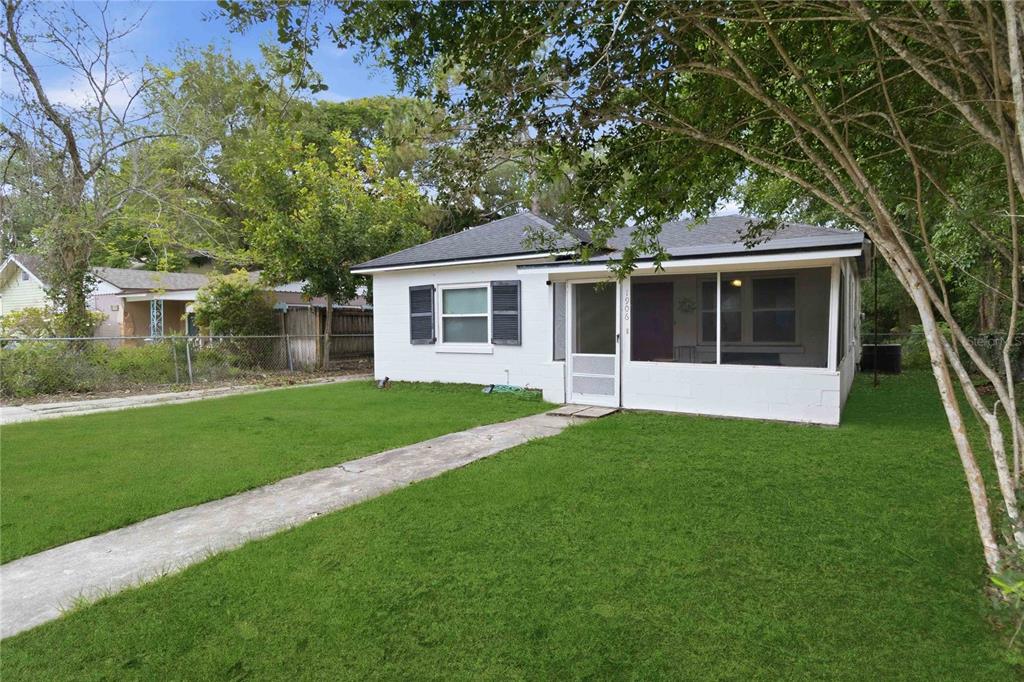 A white, single-story house with a screened-in front porch sits behind a concrete walkway — 1906 MAE STREET, ORLANDO, FL