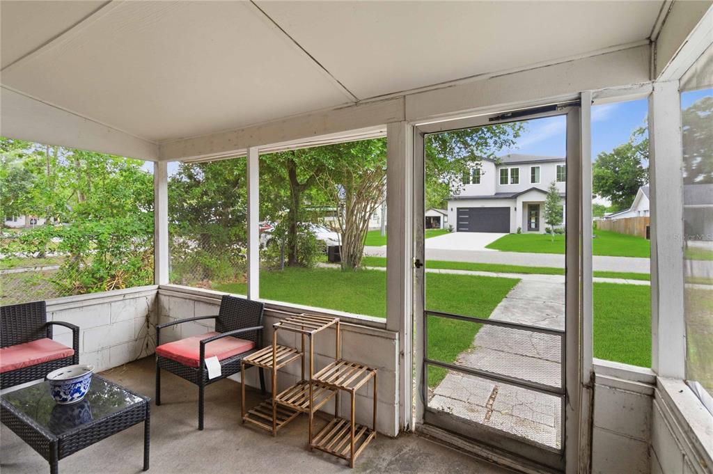 A screened-in porch with patio furniture overlooks a residential street and a modern house — 1906 MAE STREET, ORLANDO, FL