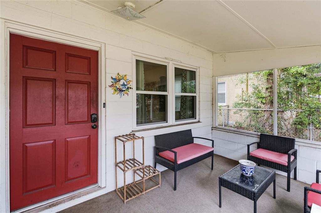 A covered porch features a red front door, wicker furniture, and a concrete floor — 1906 MAE STREET, ORLANDO, FL
