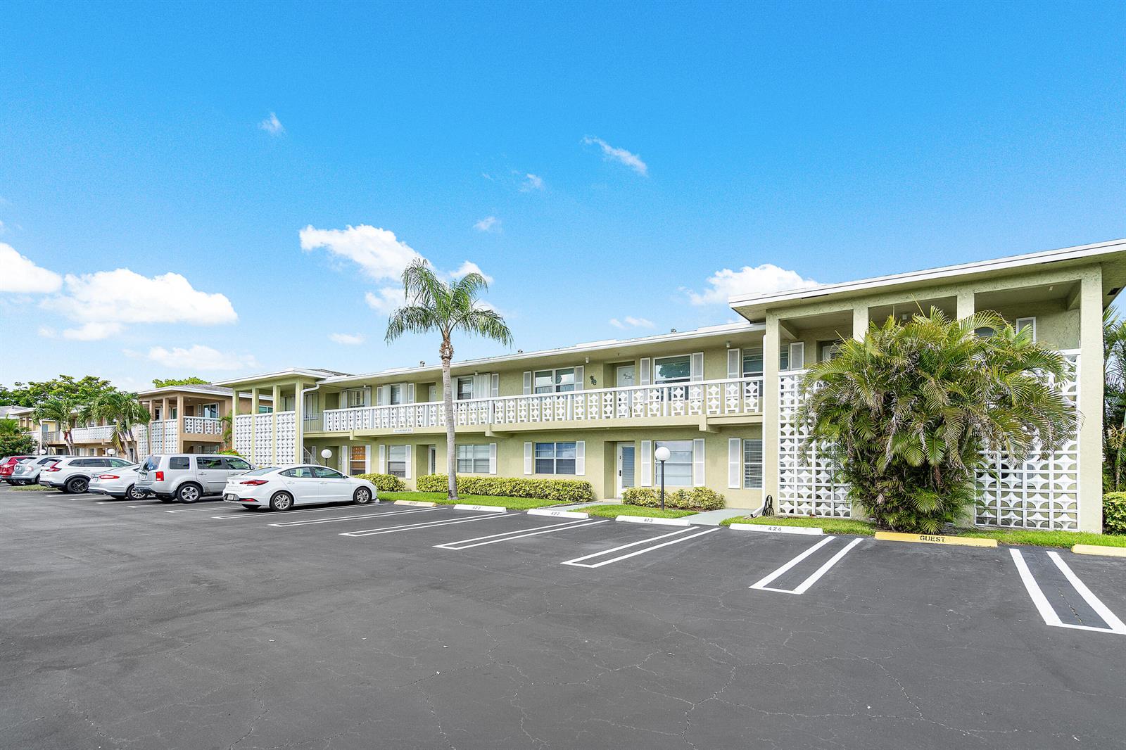 A multi-story apartment building with a parking lot in the foreground under a blue sky — 1021 Flame Vine Avenue # 104, Delray Beach FL 33445, DELRAY BEACH, FL