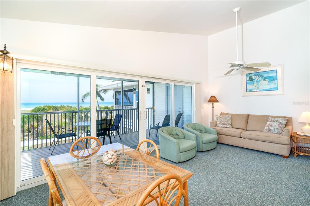 A living and dining area with a glass-topped table, sofa, and sliding doors to a balcony — 7438 PALM ISLAND DRIVE UNIT 3721, PLACIDA, FL