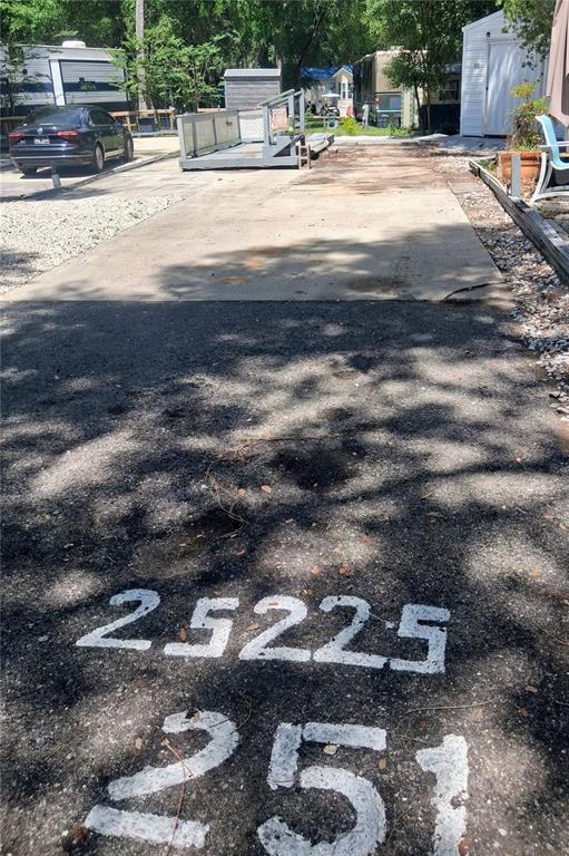 An outdoor concrete pad for a recreational vehicle is marked with painted numbers on asphalt — 25225 141ST LANE NE, FORT MC COY, FL