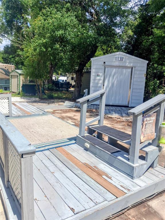 A wooden deck with stairs leads to a metal storage shed in a wooded yard — 25225 141ST LANE NE, FORT MC COY, FL