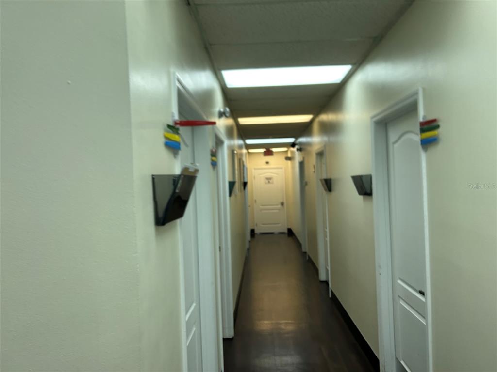 A narrow hallway with light-colored walls, a dark floor, and several white doors — 3300 SW 34TH AVENUE UNIT 116, OCALA, FL