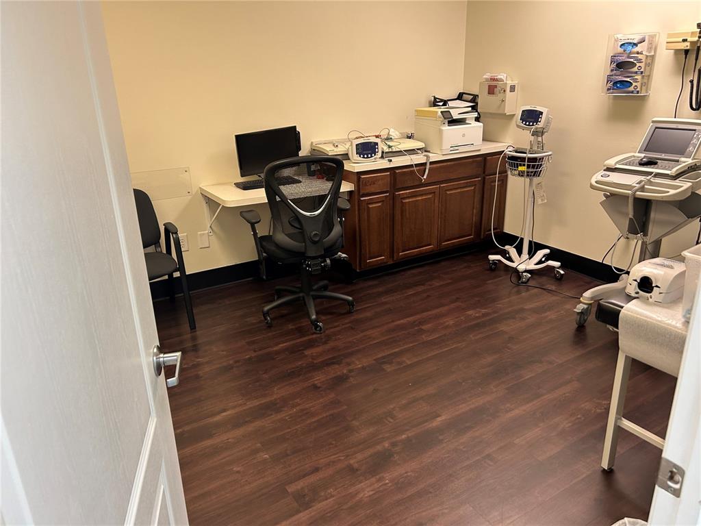 A medical office room features wood-look flooring, a desk with a computer, and medical equipment — 3300 SW 34TH AVENUE UNIT 116, OCALA, FL