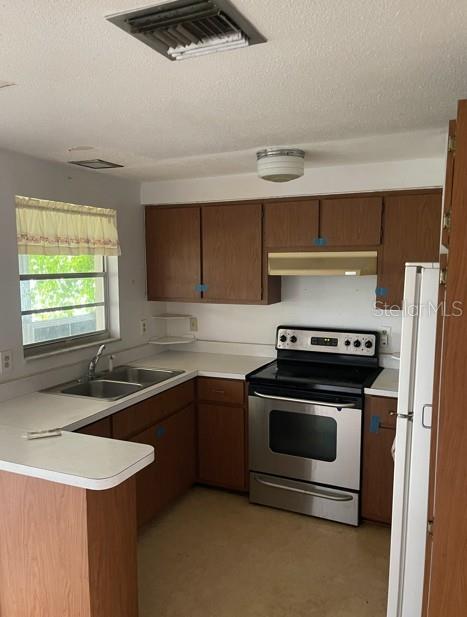 A kitchen features wood cabinets, a stainless steel stove, and a window with a valance — 21084 QUESADA AVENUE, PORT CHARLOTTE, FL