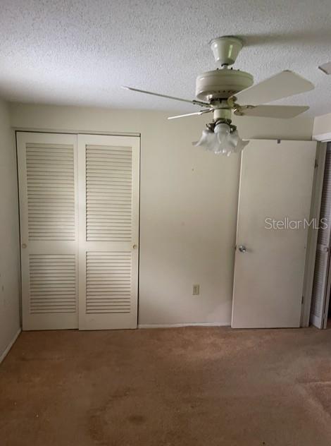 A bedroom with beige carpet, a ceiling fan, louvered closet doors, and a white interior door — 21084 QUESADA AVENUE, PORT CHARLOTTE, FL