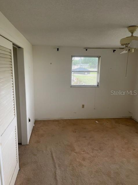 An empty bedroom features beige carpeting, a ceiling fan, and a window overlooking the outdoors — 21084 QUESADA AVENUE, PORT CHARLOTTE, FL