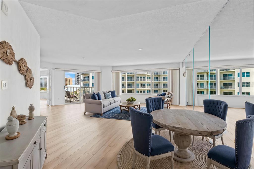A bright, open-concept living and dining area features light wood floors and floor-to-ceiling windows — 3 OCEANS WEST BOULEVARD UNIT 6C4, DAYTONA BEACH SHORES, FL