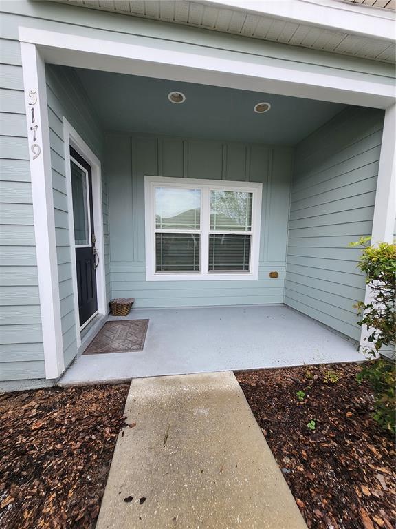 A covered front porch features light blue siding, a dark door, and a concrete walkway — 5179 NW 22ND STREET, GAINESVILLE, FL