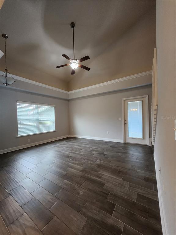 A room with a vaulted ceiling, ceiling fan, window blinds, and dark wood-look tile flooring — 5179 NW 22ND STREET, GAINESVILLE, FL