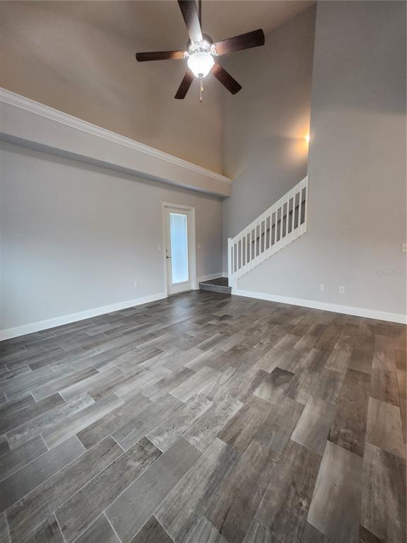 A living room with high ceilings, a ceiling fan, wood-look tile flooring, and a staircase — 5179 NW 22ND STREET, GAINESVILLE, FL