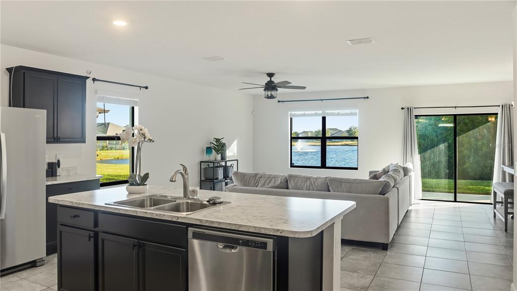 A kitchen island with a sink overlooks a living area with a view of a lake — 5954 ORSINO LANE, COCOA, FL