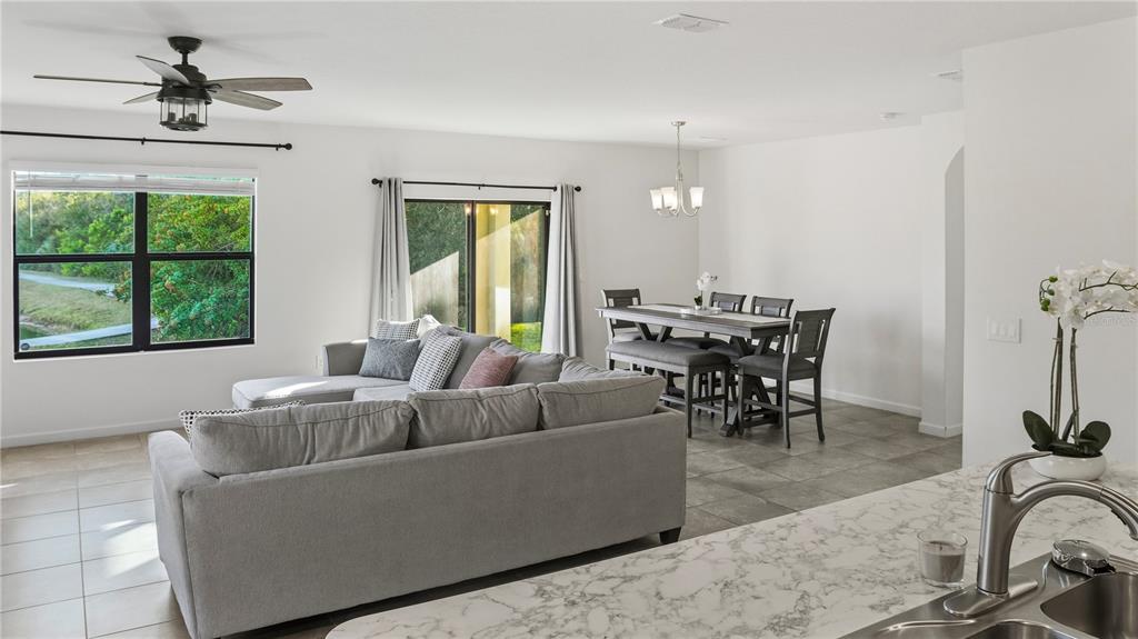 An open-concept living and dining area features a gray sectional sofa and a dining set — 5954 ORSINO LANE, COCOA, FL