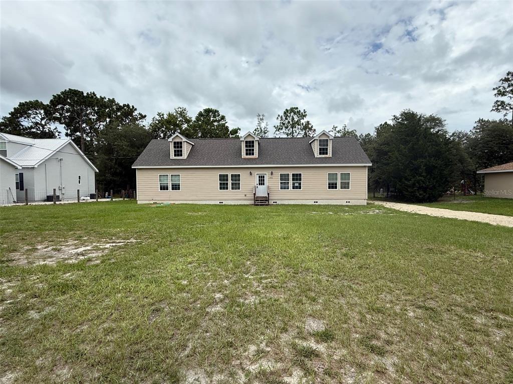 A beige, single-story house with three dormer windows sits on a large, grassy lot — 11970 OSPREY AVENUE, WEEKI WACHEE, FL
