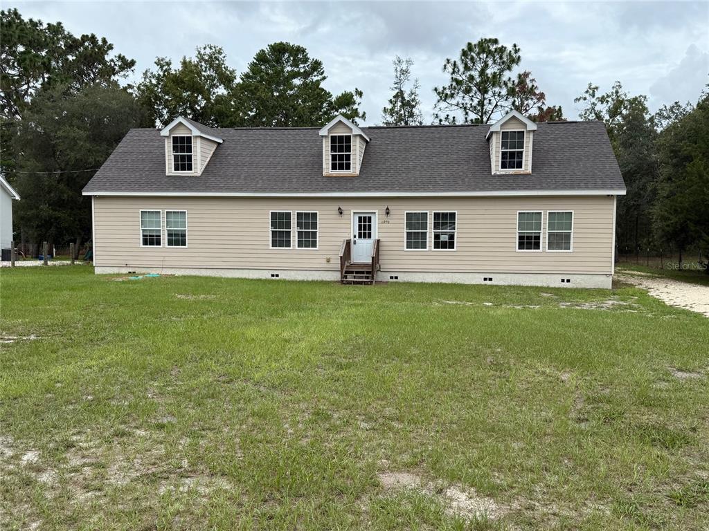 A tan, single-story house with a gray roof and three dormer windows sits on grass — 11970 OSPREY AVENUE, WEEKI WACHEE, FL