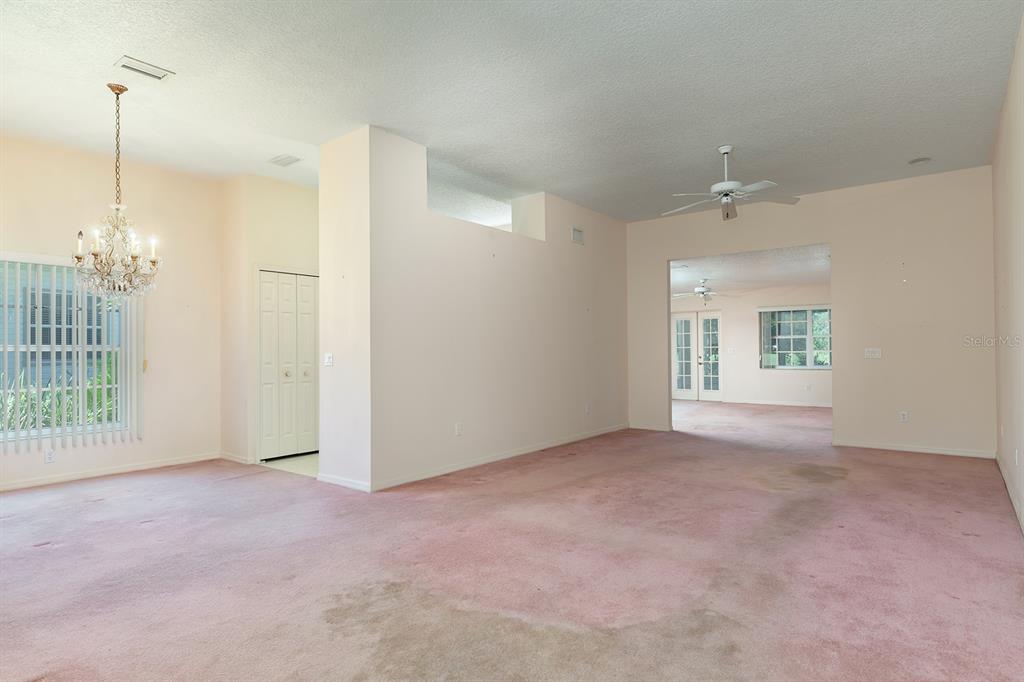 A spacious room with pink carpeting, a crystal chandelier, and a ceiling fan — 167 JUNIPER WAY, TAVARES, FL