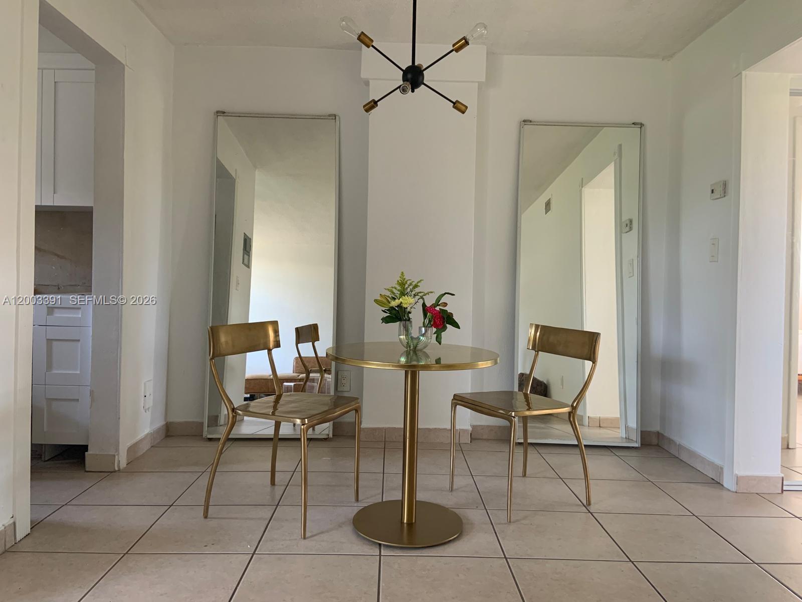 A dining area features a round gold table, two gold chairs, and two large floor mirrors — 360 Meridian Ave # 4C, Miami Beach FL 33139, MIAMI BEACH, FL
