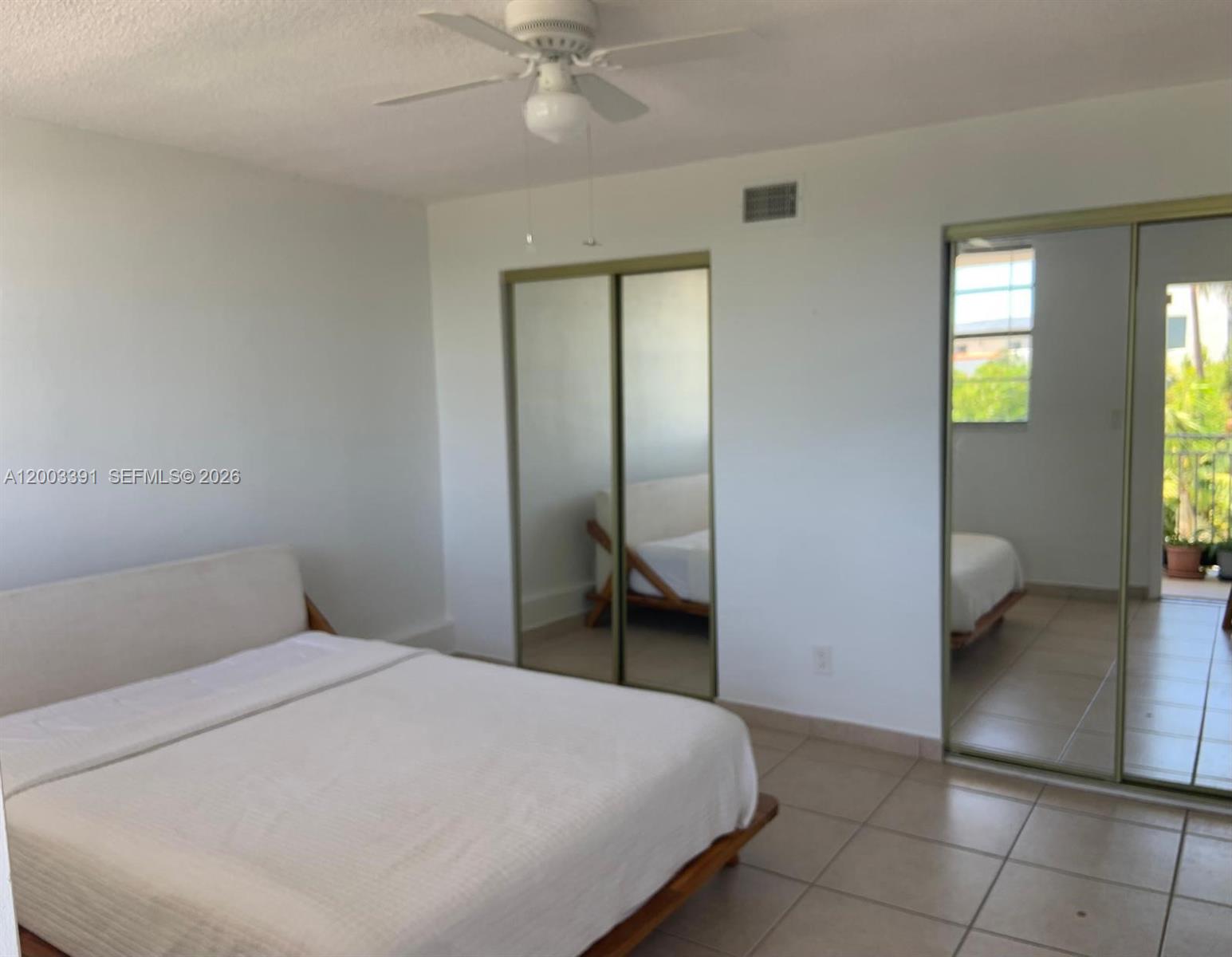 A bedroom features a bed, tiled floors, a ceiling fan, and mirrored closet doors — 360 Meridian Ave # 4C, Miami Beach FL 33139, MIAMI BEACH, FL