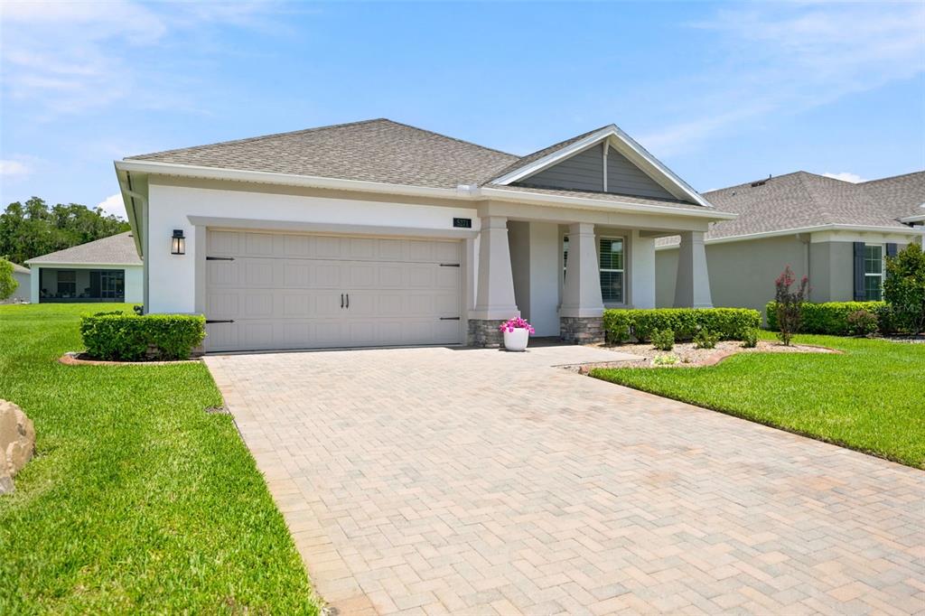 A single-story house with a beige garage, stone-accented columns, and a paved driveway — 5271 CAPPLEMAN LOOP, BROOKSVILLE, FL