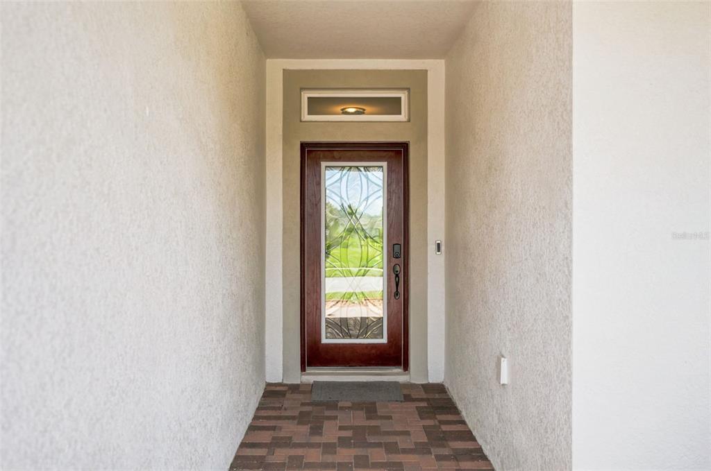 A front entryway features a wooden door with a glass insert and a transom window — 5271 CAPPLEMAN LOOP, BROOKSVILLE, FL