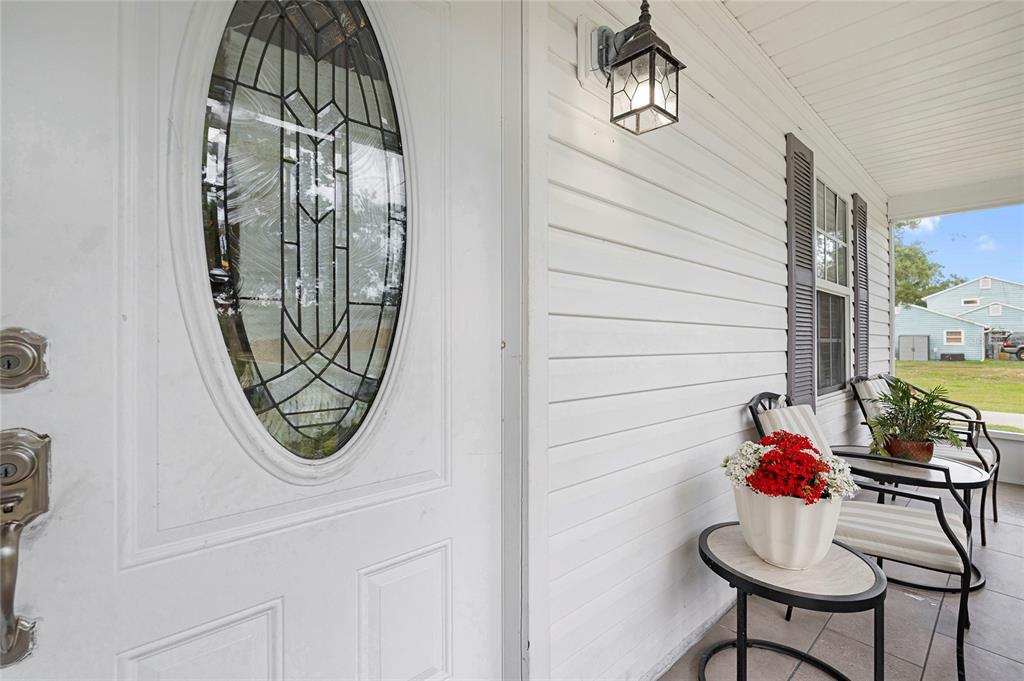 A white front door with a decorative oval window sits on a covered porch — 7067 JARVIS ROAD, SARASOTA, FL