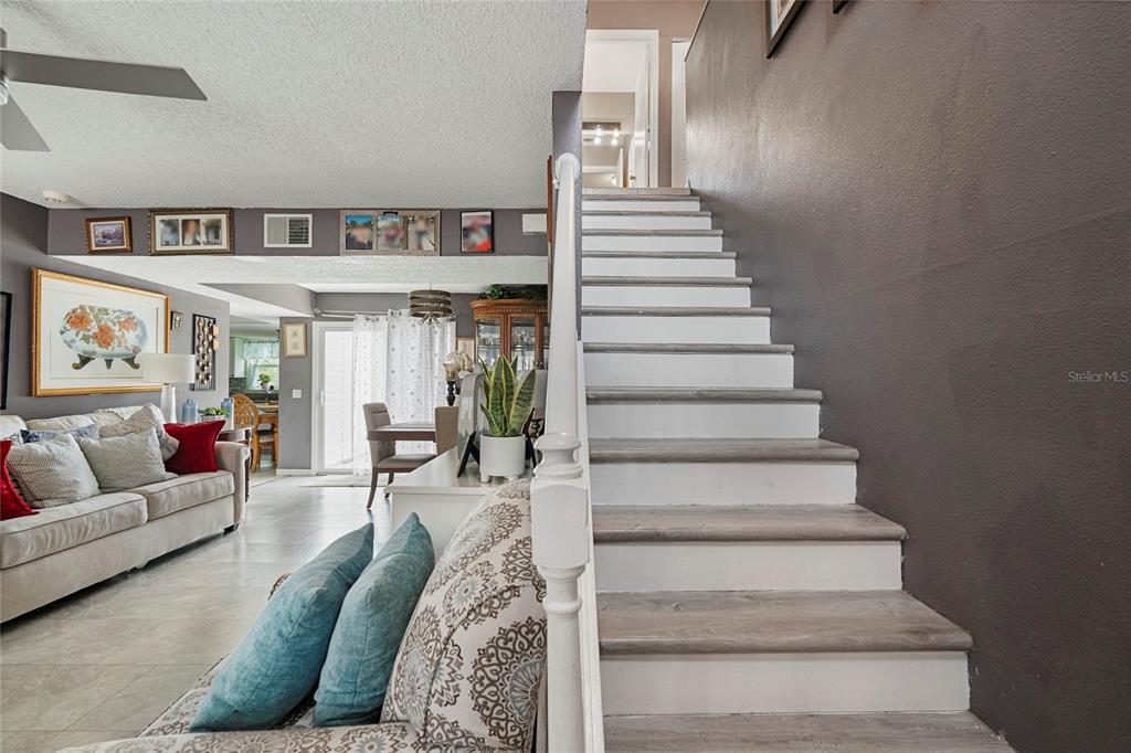 A living room features a staircase with white risers and wood-look treads — 7067 JARVIS ROAD, SARASOTA, FL
