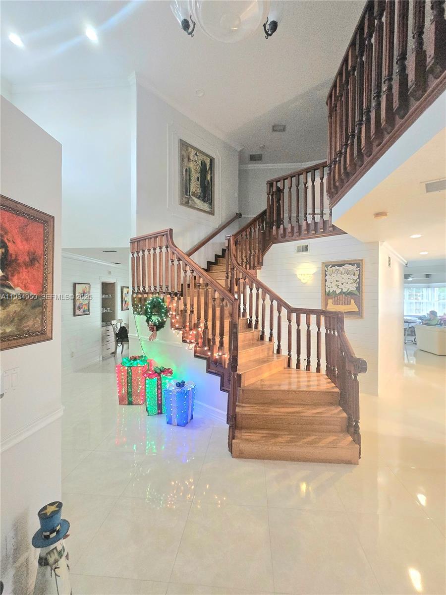 A grand foyer features a wooden staircase with decorative railings and festive holiday decorations — 16422 NW 83rd Pl, Miami Lakes FL 33016, MIAMI LAKES, FL