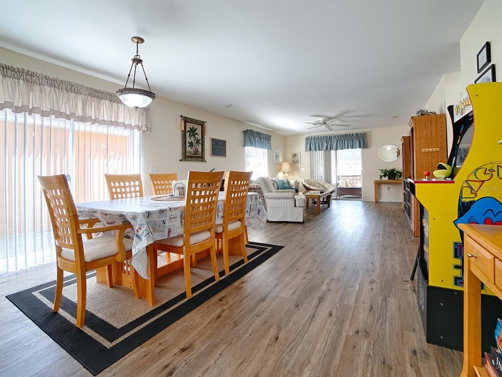 A dining area with a wooden table and chairs sits adjacent to a living room — 1106 RICARDO AVENUE, THE VILLAGES, FL