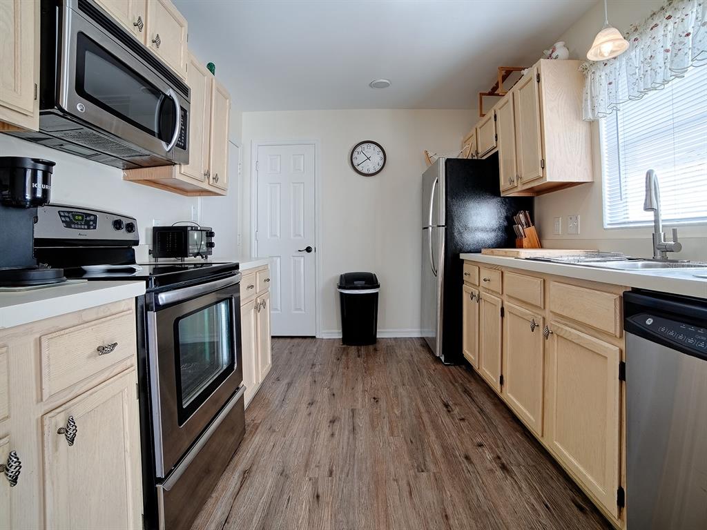 A kitchen with light wood cabinets, stainless steel appliances, and wood-look flooring — 1106 RICARDO AVENUE, THE VILLAGES, FL