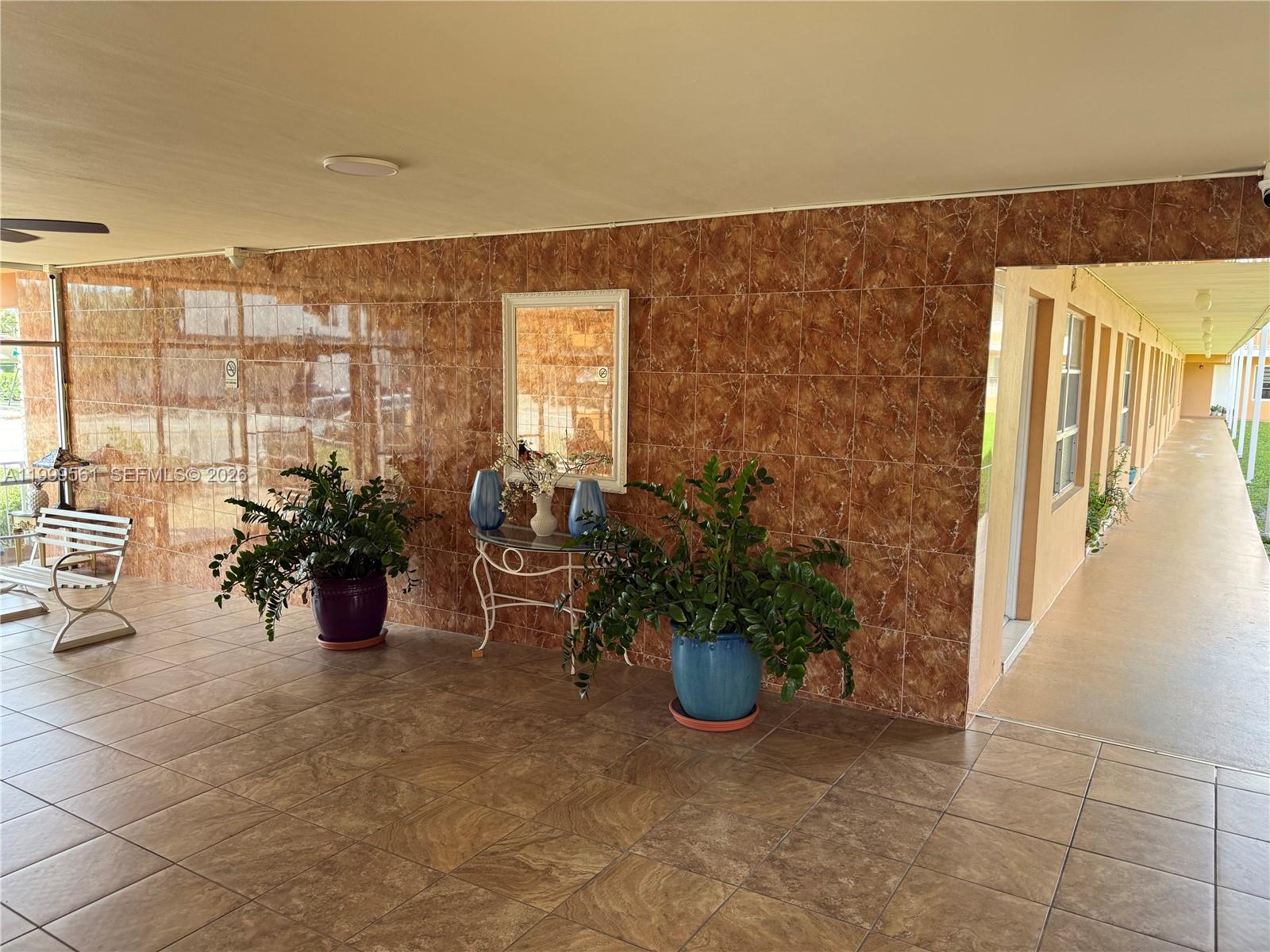 A covered outdoor patio features brown tiled walls and floors, potted plants, and a console table — 3881 W Flagler St # 319, Miami FL 33134, MIAMI, FL