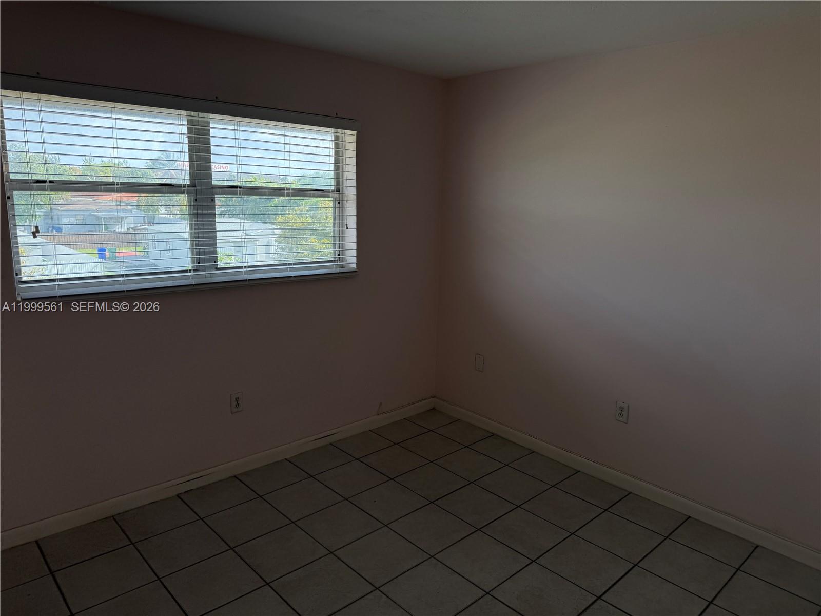 An empty room features light-colored walls, tiled flooring, and a window with horizontal blinds — 3881 W Flagler St # 319, Miami FL 33134, MIAMI, FL