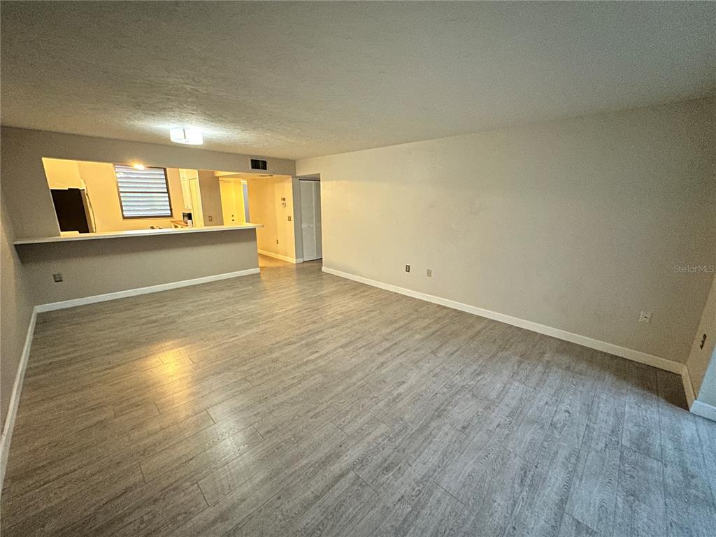 An open living area features light gray wood-look flooring and a kitchen pass-through window — 283 SHERWOOD DRIVE UNIT 283U, BRADENTON, FL
