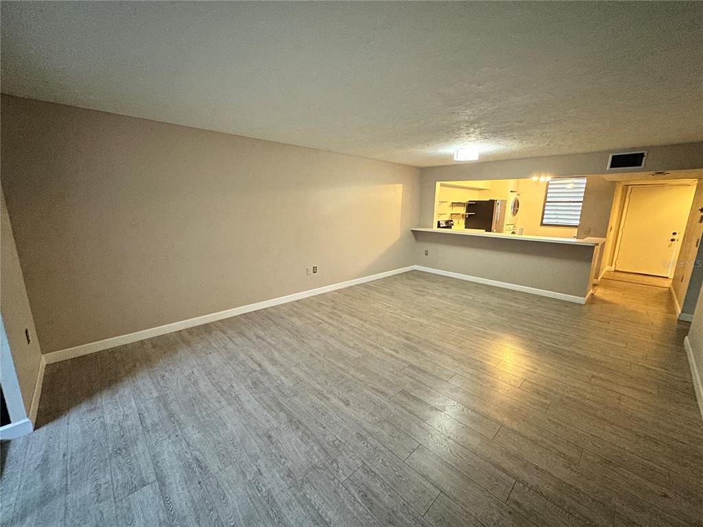 An empty living room features light gray wood-look flooring and a kitchen pass-through counter — 283 SHERWOOD DRIVE UNIT 283U, BRADENTON, FL