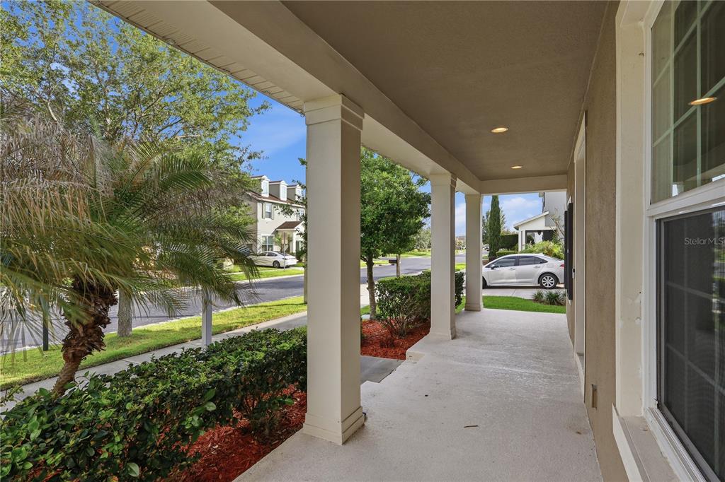 A two-story suburban house features a front porch, a garage, and a landscaped yard — 32659 HARMONY OAKS DRIVE, WESLEY CHAPEL, FL