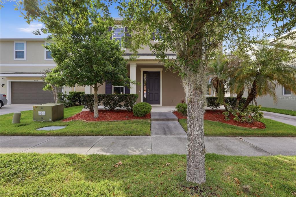 A covered front porch with white columns overlooks a residential street and a parked car — 32659 HARMONY OAKS DRIVE, WESLEY CHAPEL, FL