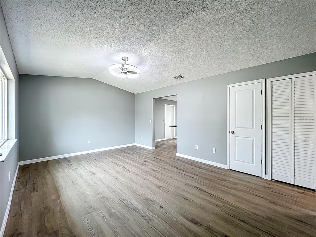 An empty bedroom features light gray walls, wood-look flooring, a ceiling fan, and white doors — 6848 COMPASS COURT, ORLANDO, FL