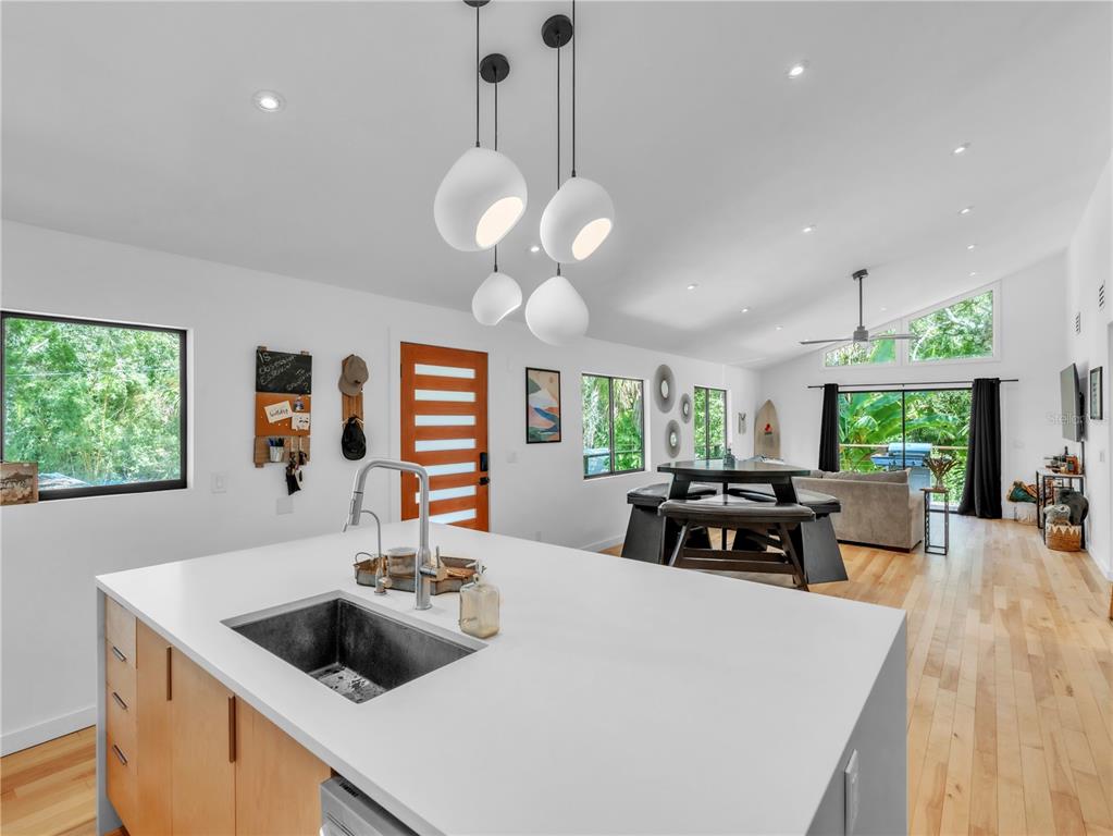 A modern kitchen with a white island and pendant lights overlooks an open living area — 43 HAMILTON HEATH DRIVE, TAMPA, FL