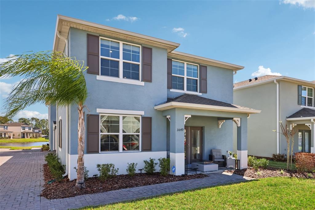 A two-story blue house with brown shutters, a covered front porch, and a paved walkway — 3049 MELETO BOULEVARD, NEW SMYRNA BEACH, FL