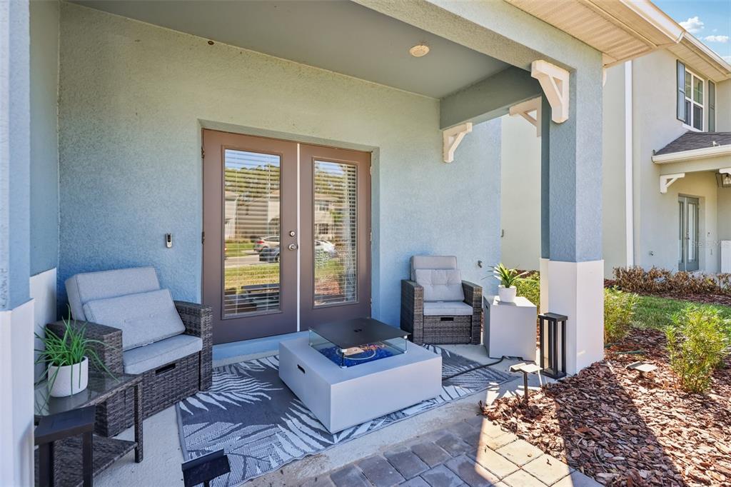 A covered patio features two wicker chairs, a fire pit, and a patterned area rug — 3049 MELETO BOULEVARD, NEW SMYRNA BEACH, FL