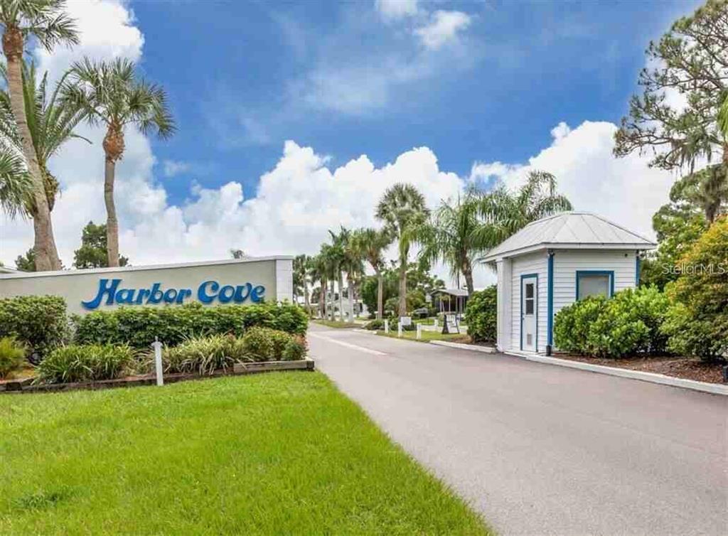 A paved road leads past a Harbor Cove entrance sign and a small guardhouse — 234 TRAILORAMA DRIVE, NORTH PORT, FL