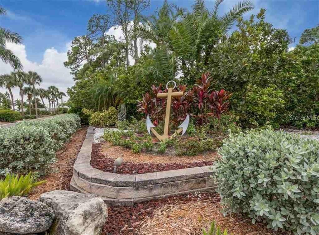 A large decorative anchor sits in a landscaped garden bed with a stone retaining wall — 234 TRAILORAMA DRIVE, NORTH PORT, FL
