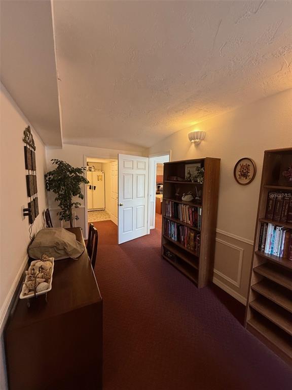 A hallway with red carpeting, two wooden bookshelves, and a white door leading to another room — 5422 TROUBLE CREEK ROAD, NEW PORT RICHEY, FL