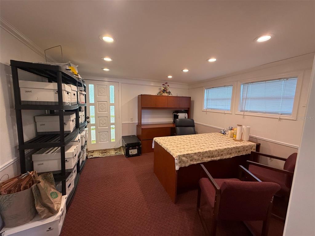 A home office features a desk, two chairs, storage shelving, and a glass-paneled entry door — 5422 TROUBLE CREEK ROAD, NEW PORT RICHEY, FL