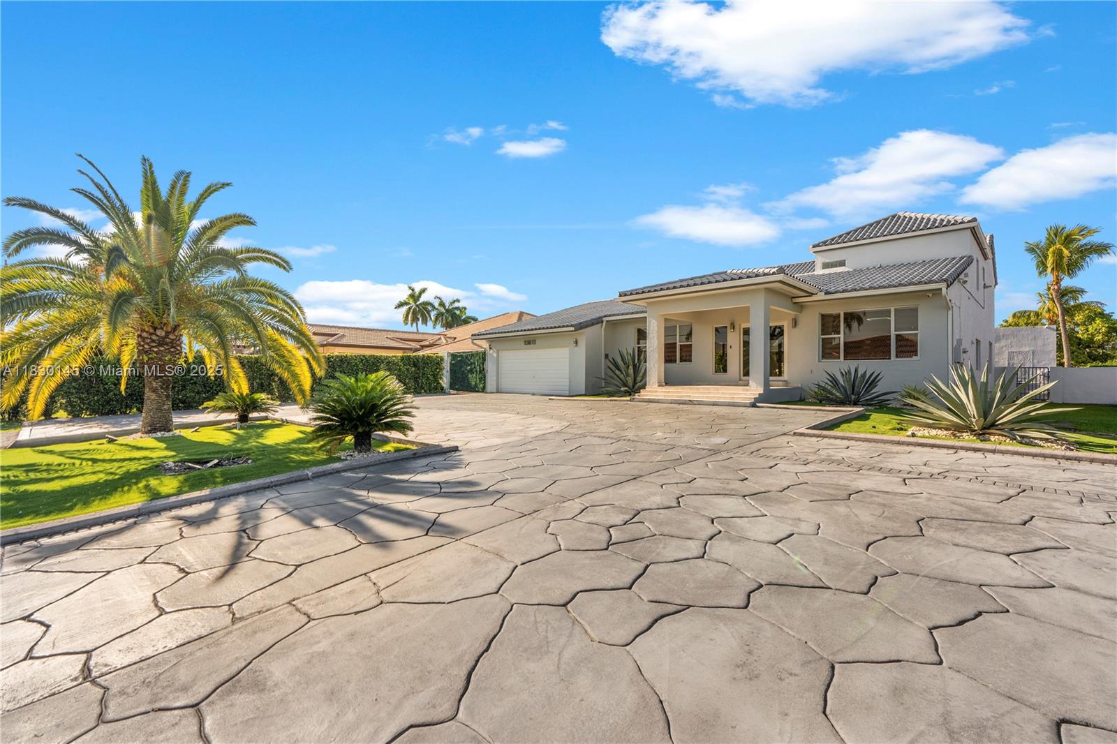 A single-story house with a large stone-patterned driveway and palm trees under a blue sky — 13815 SW 38th St, Miami FL 33175, MIAMI, FL