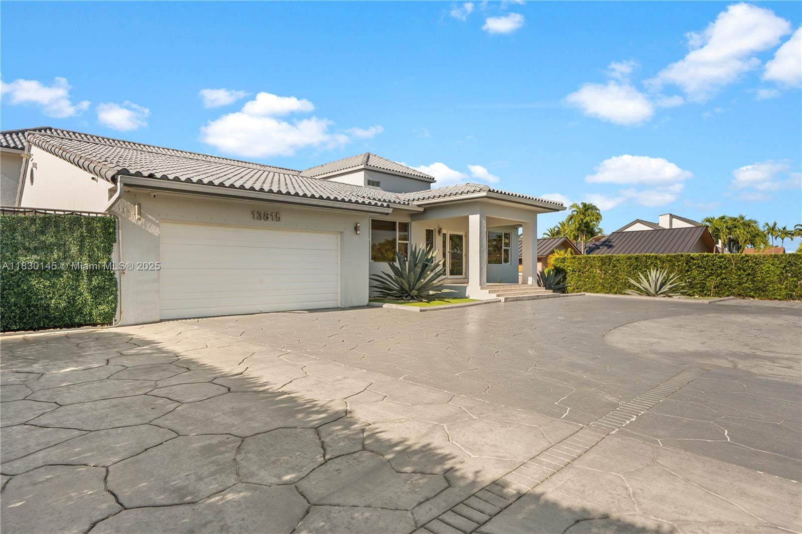 A single-story house with a tiled roof, white garage door, and a large paved driveway — 13815 SW 38th St, Miami FL 33175, MIAMI, FL