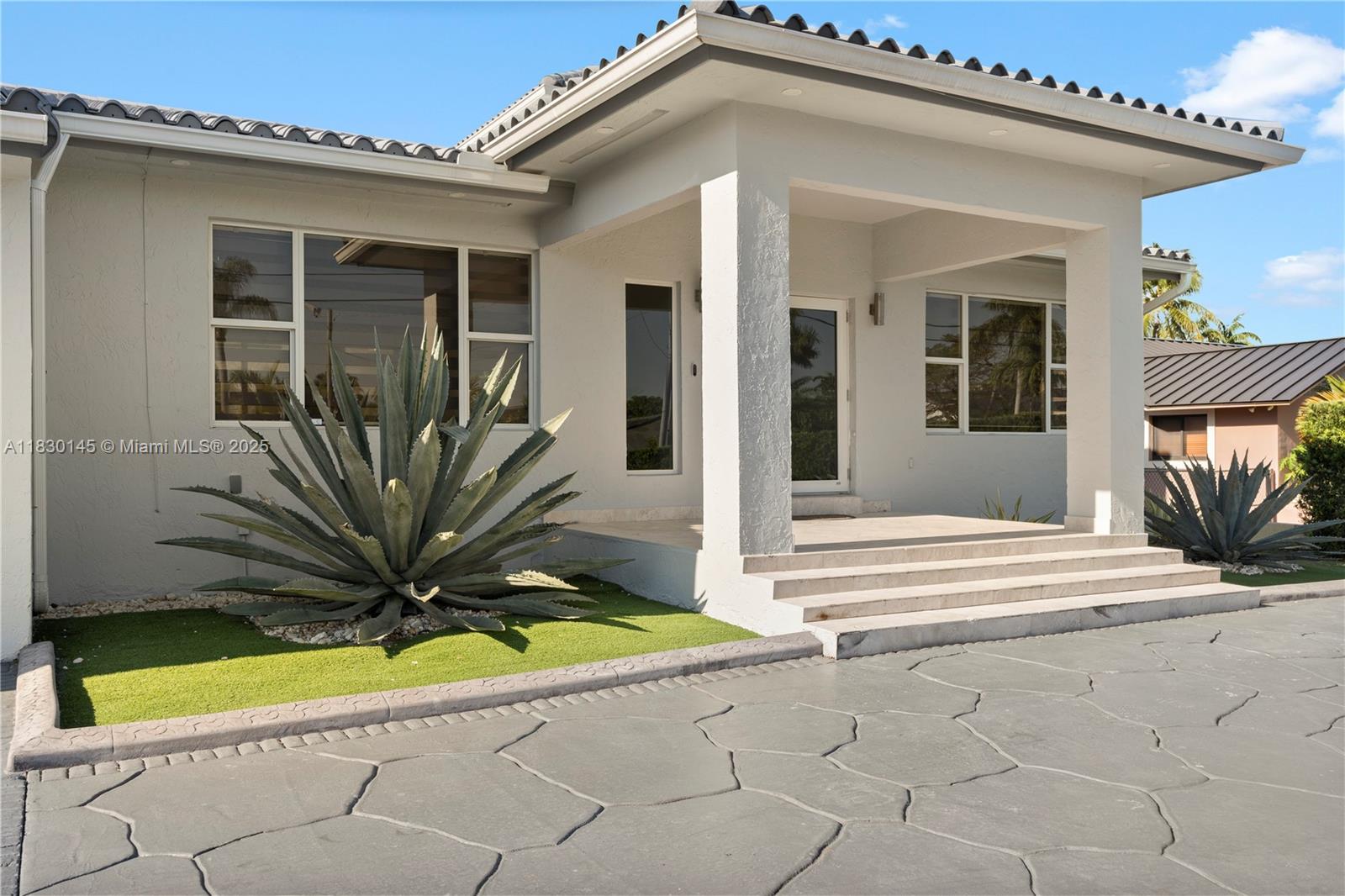 The exterior of a light-colored house features a covered entryway, stone steps, and agave plants — 13815 SW 38th St, Miami FL 33175, MIAMI, FL