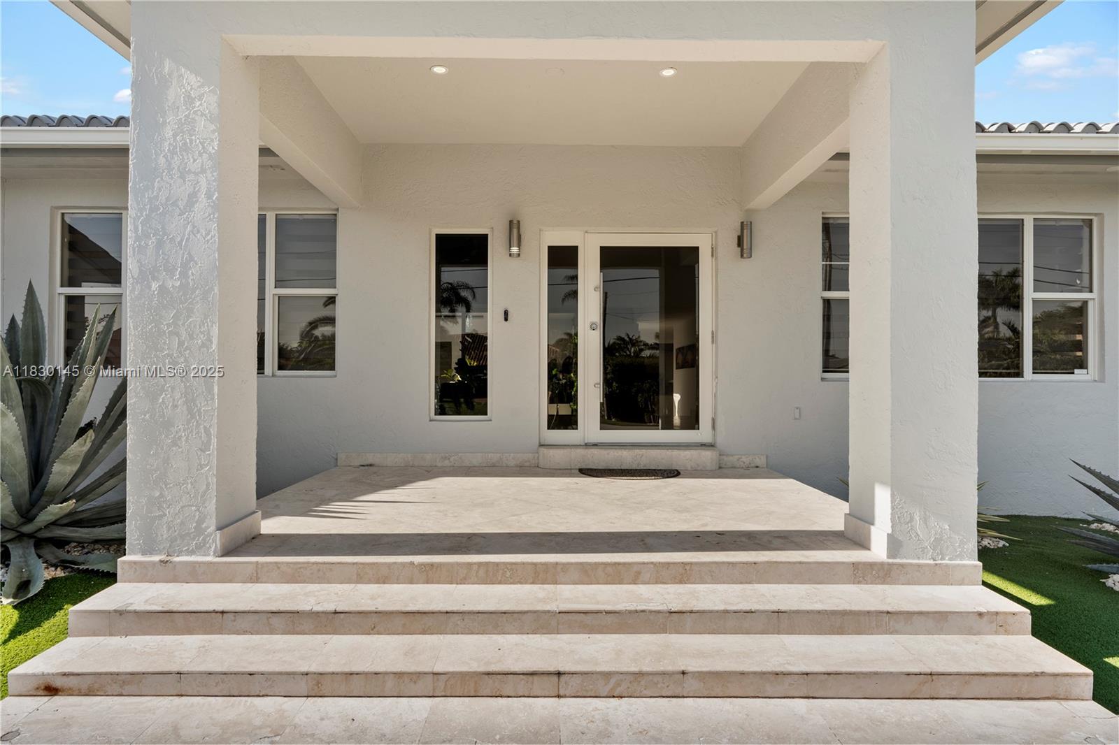 A white house exterior features a covered entryway with stone steps and glass doors — 13815 SW 38th St, Miami FL 33175, MIAMI, FL