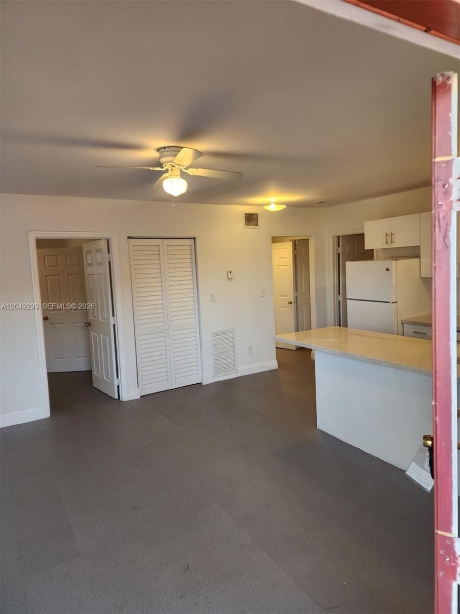 An interior view shows a kitchen with a breakfast bar, white cabinets, and gray flooring — 14240 NW 22nd Ave # 3, Opa-Locka FL 33054, OPA-LOCKA, FL